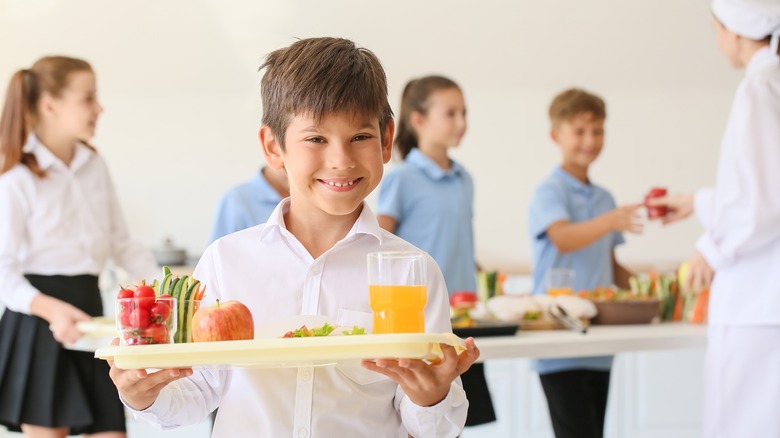 boy smiling holding school lunch