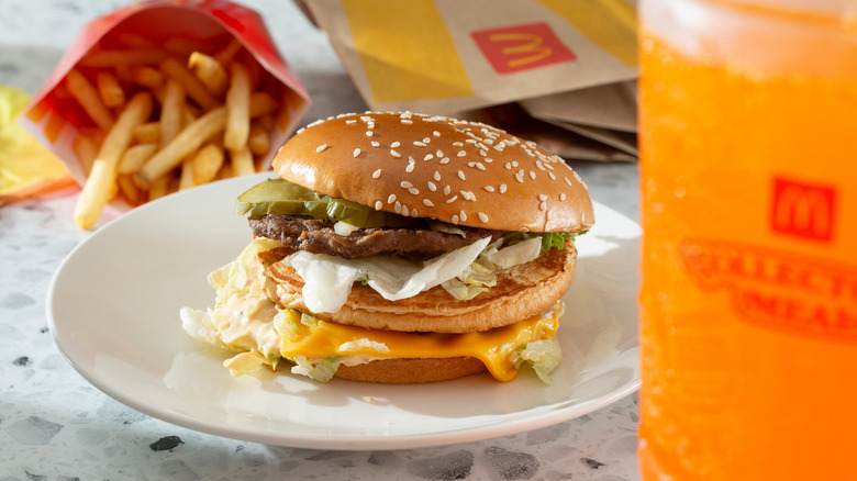 Plated Big Mac combo meal with fries in the back and an orange soda in the foreground