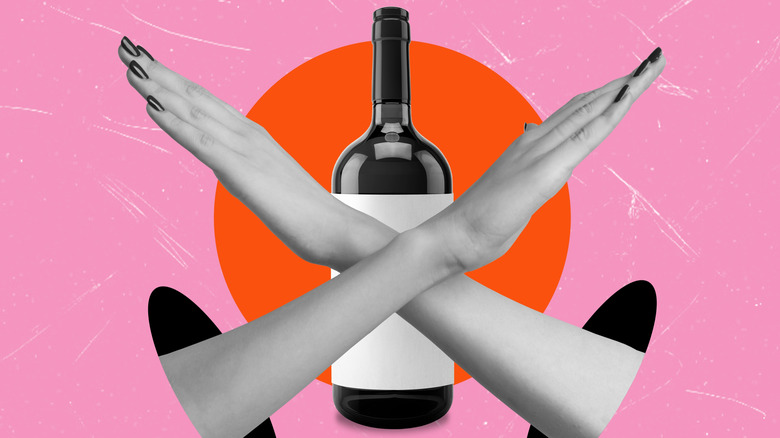 Two hands crossing overtop a bottle of wine