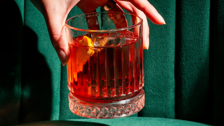 A hand holding a glass with a cocktail