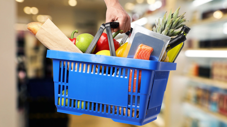A full grocery basket being held in the air at a store