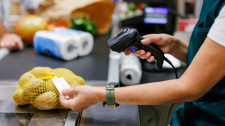 A grocery store employee scanning potatoes at the register