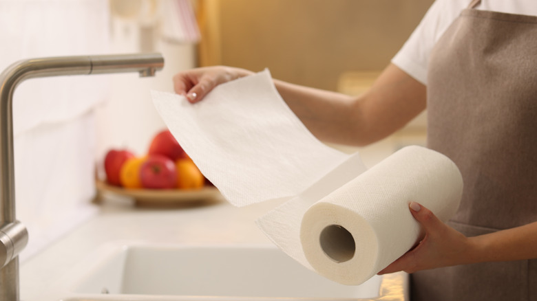 Hands ripping paper towel from roll in kitchen