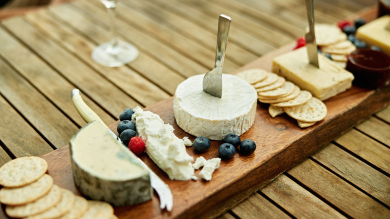 Soft cheeses laid out on a wooden board and table