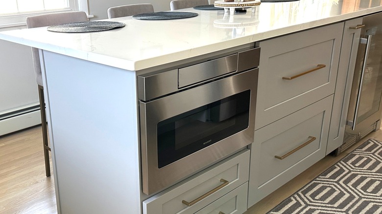 Stainless steel microwave built into white kitchen island