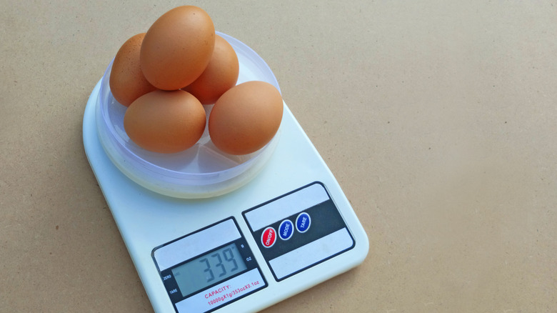 Three eggs being weighed on a white digital scale