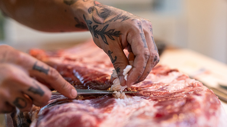 Person carving fat from a cut of beef for pot roast