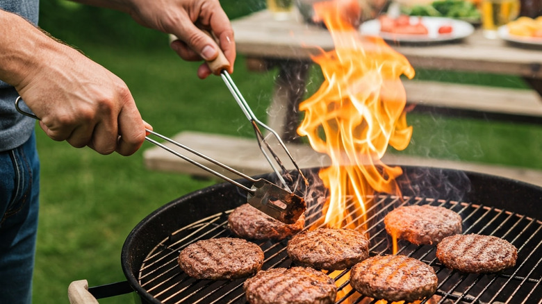 Home cook grilling burgers on a charcoal grill outdoors