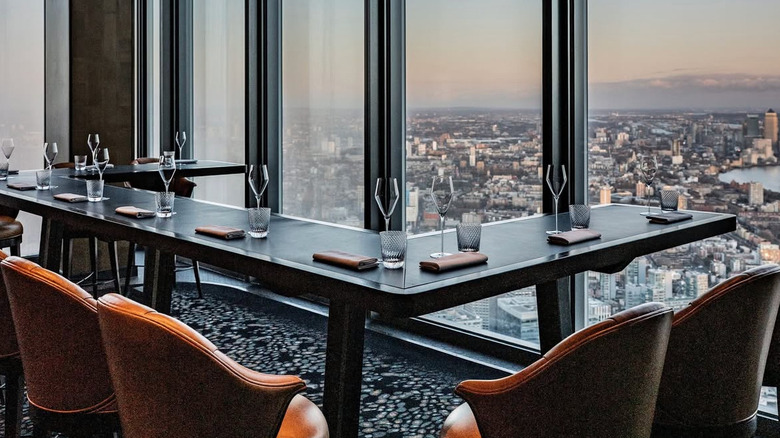 Table and chairs at Restaurant Gordon Ramsay High with views of London through window from above