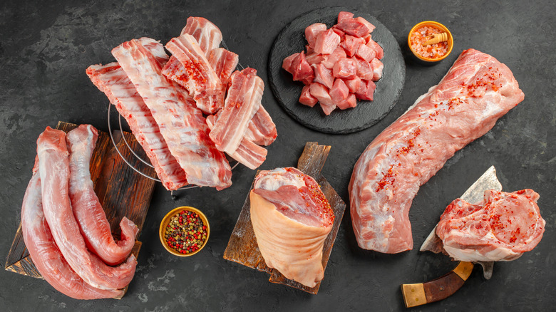 Various cuts of raw pork displayed on cutting boards and slate plates.