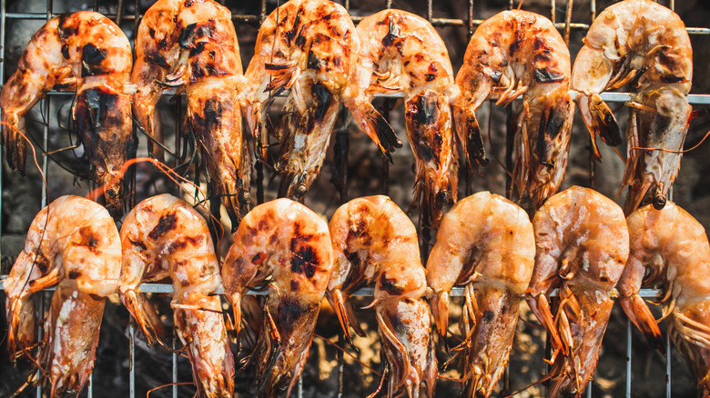 head-on shrimp on a skewer with grill marks on the grill