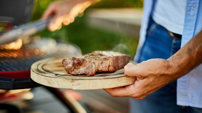 Man taking a steak off the grill