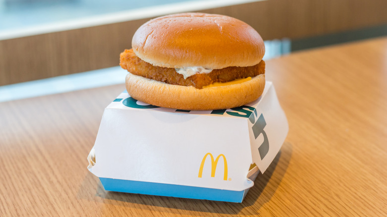 McDonald's Filet-O-Fish sandwich sitting on top of white cardboard box on wooden table