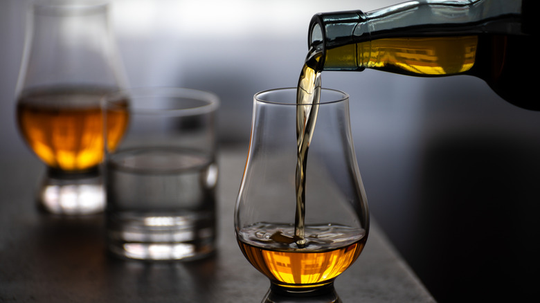 pouring a glass of scotch with a glass of water in background