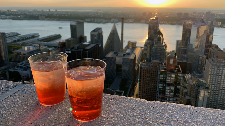 Two iced drinks sit on a ledge overlooking the skyline of New York City