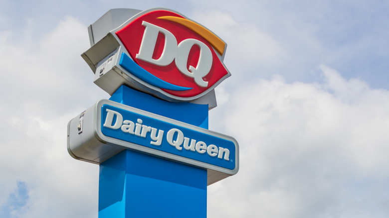 A Dairy Queen sign against a cloudy sky.