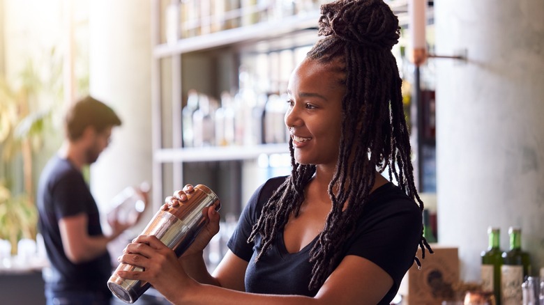 Female bartender shaking a cocktail shaker at a bar