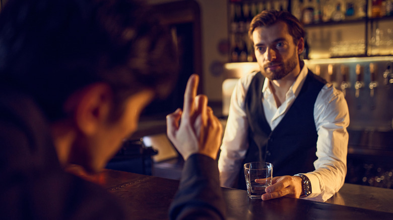 Man ordering at a bar with the bartender listening