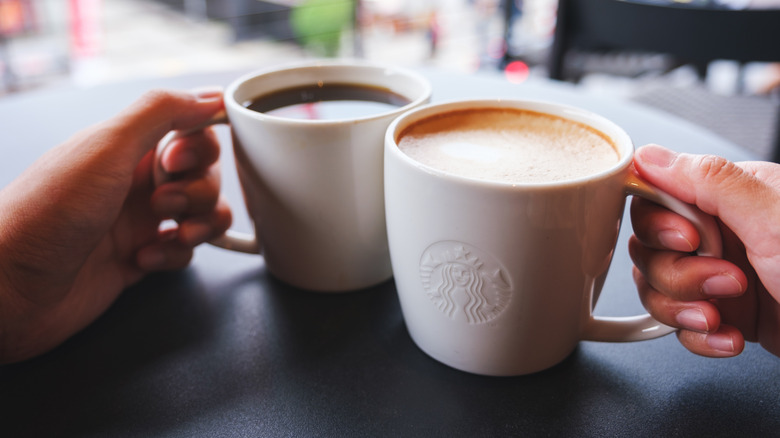 A couple clinking Starbucks mugs together