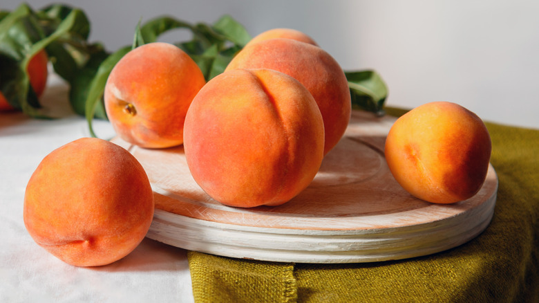 Five peaches on a cutting board