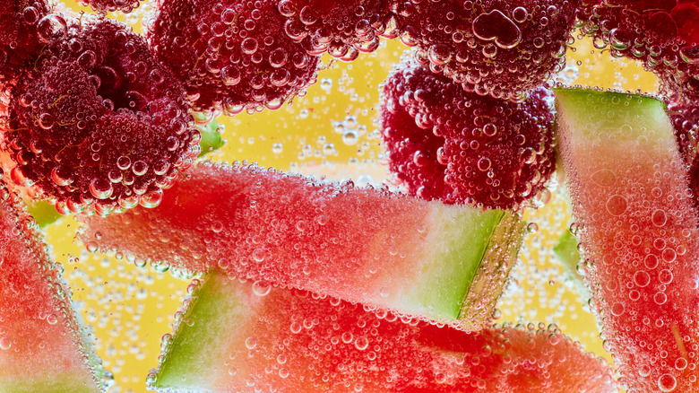 Raspberries, lemon and watermelon in fizzy water close-up