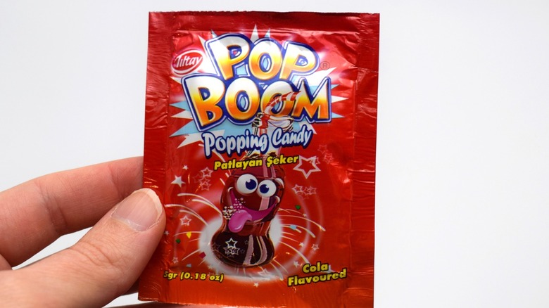 a hand holding a pack of popping candy