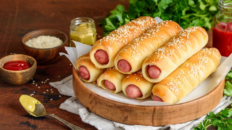 a plate of pretzel dogs surrounded by condiments