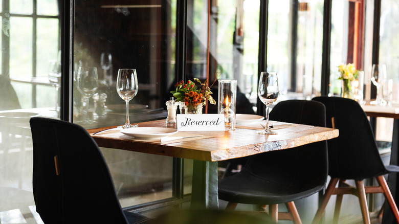 A two-top table at a restaurant with a "Reserved" sign on it