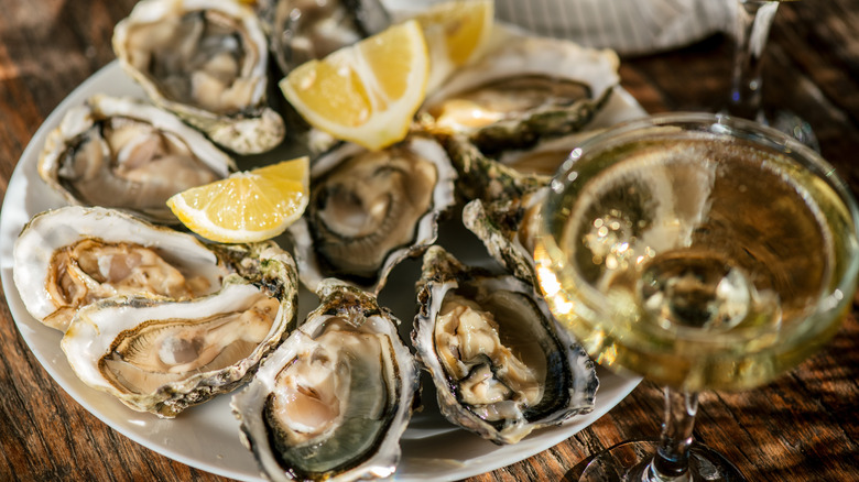 A platter of oysters with lemon wedges; a glass of champagne foregrounded
