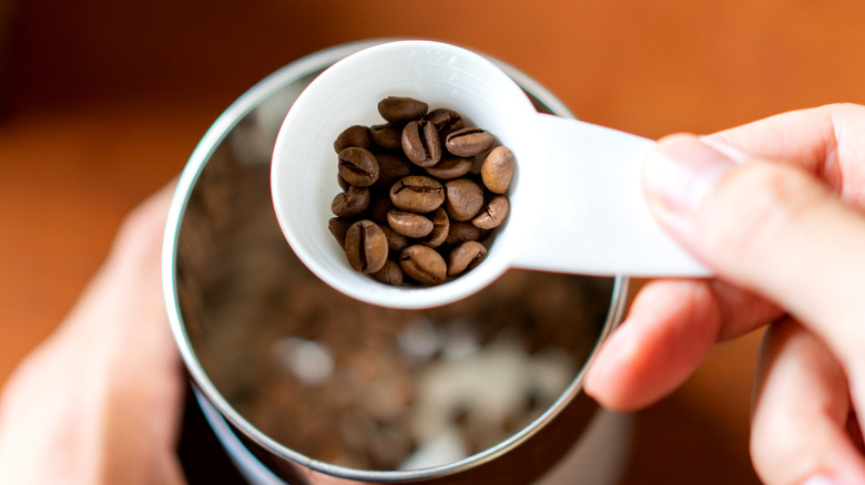 Person scooping coffee beans out of a cannister