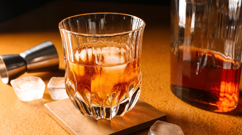 Scotch whiskey bottle, glass and old wooden barrel