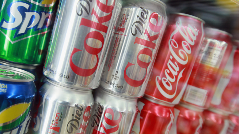 Close-up of cans of name brand soda on a shelf 