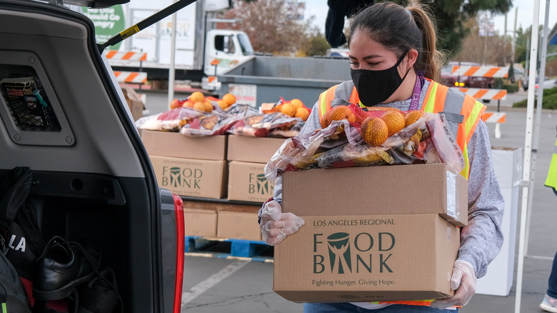 person carrying food bank box to car