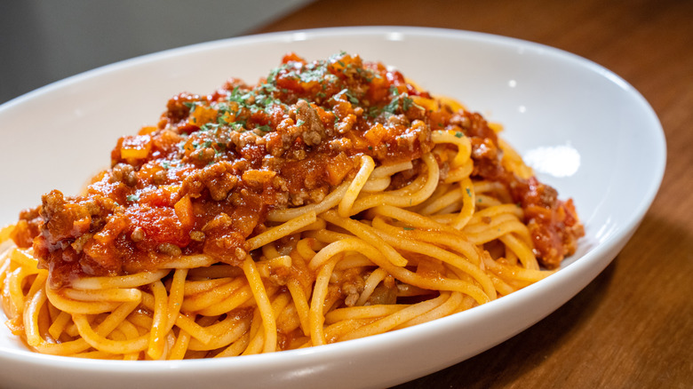 Dish of spaghetti with meat sauce on a wooden table
