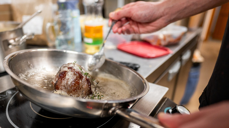 A person bastes a steak