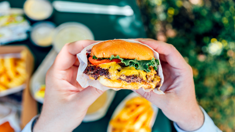 Person holding a regular size cheeseburger