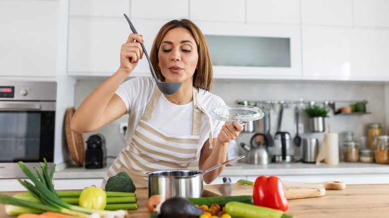 A woman tasting something over the stove