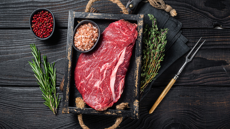 uncooked sirloin roast on black trap next to various ingredients