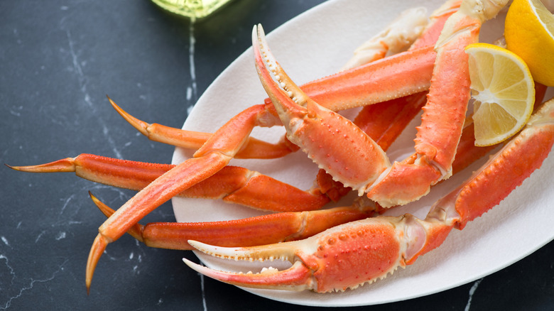 crab legs on a plate with lemon wedges