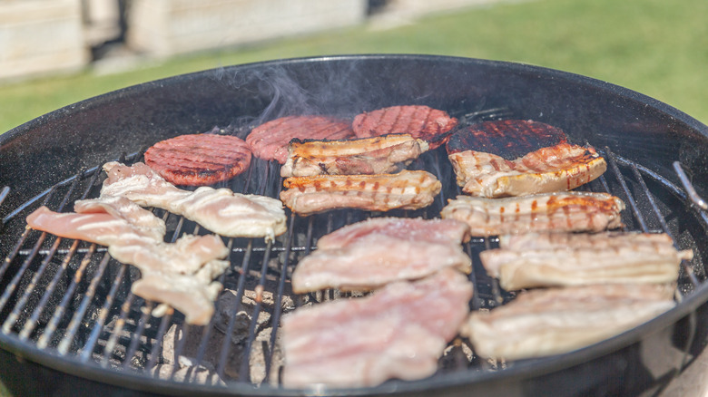 burgers, hot dogs, chicken, and bacon on a grill
