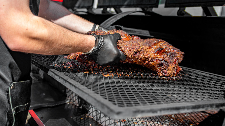 a brisket being put on a smoker