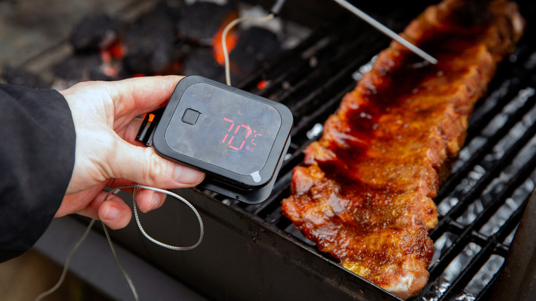 a digital thermometer being used for a rack of ribs on a grill