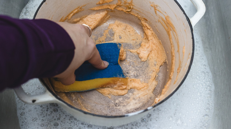 Cleaning a dirty pot with baking soda and a sponge