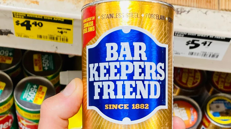 A hand holds a can of Bar Keepers Friend