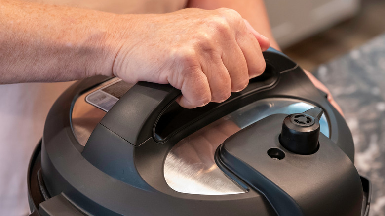 A person placing a lid on an Instant Pot device