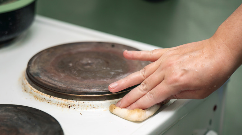 Person hand wiping a stovetop.