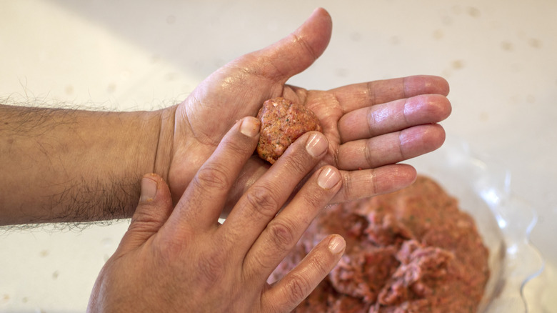 Hands forming burger patties over a bowl of ground beef