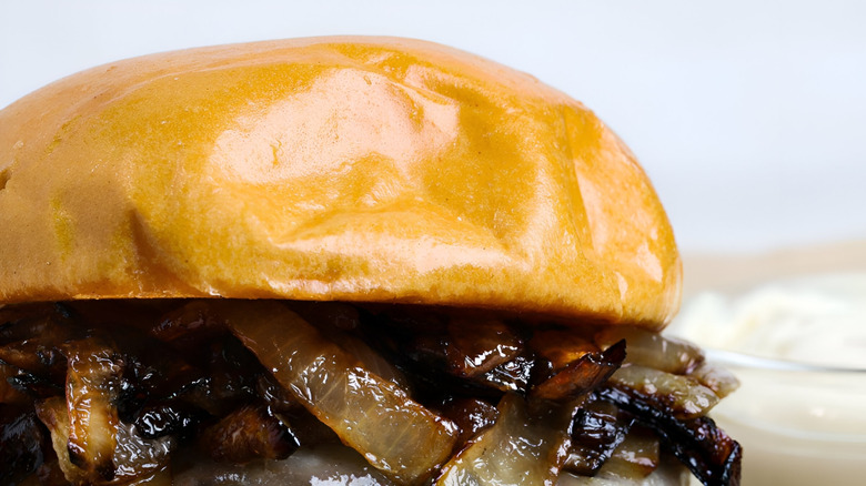 A close-up of a caramelized onion burger with a toasted brioche bun