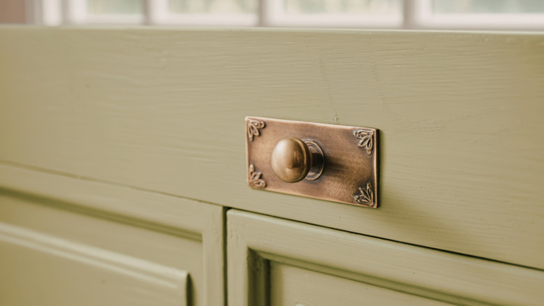 Aged brass knob on a wooden cabinet