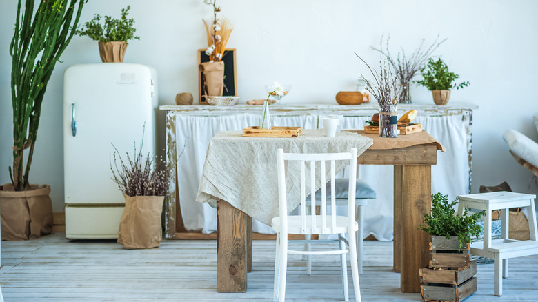 Bright bohemian kitchen interior with rustic wooden table, vintage appliances and greenery